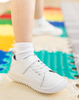 Zapatilla escolar barefoot blanca modelo Cloud con elásticos para toddler en uso vista lateral