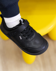 Zapatilla escolar barefoot negra modelo Dash con doble velcro para kids en uso superior
