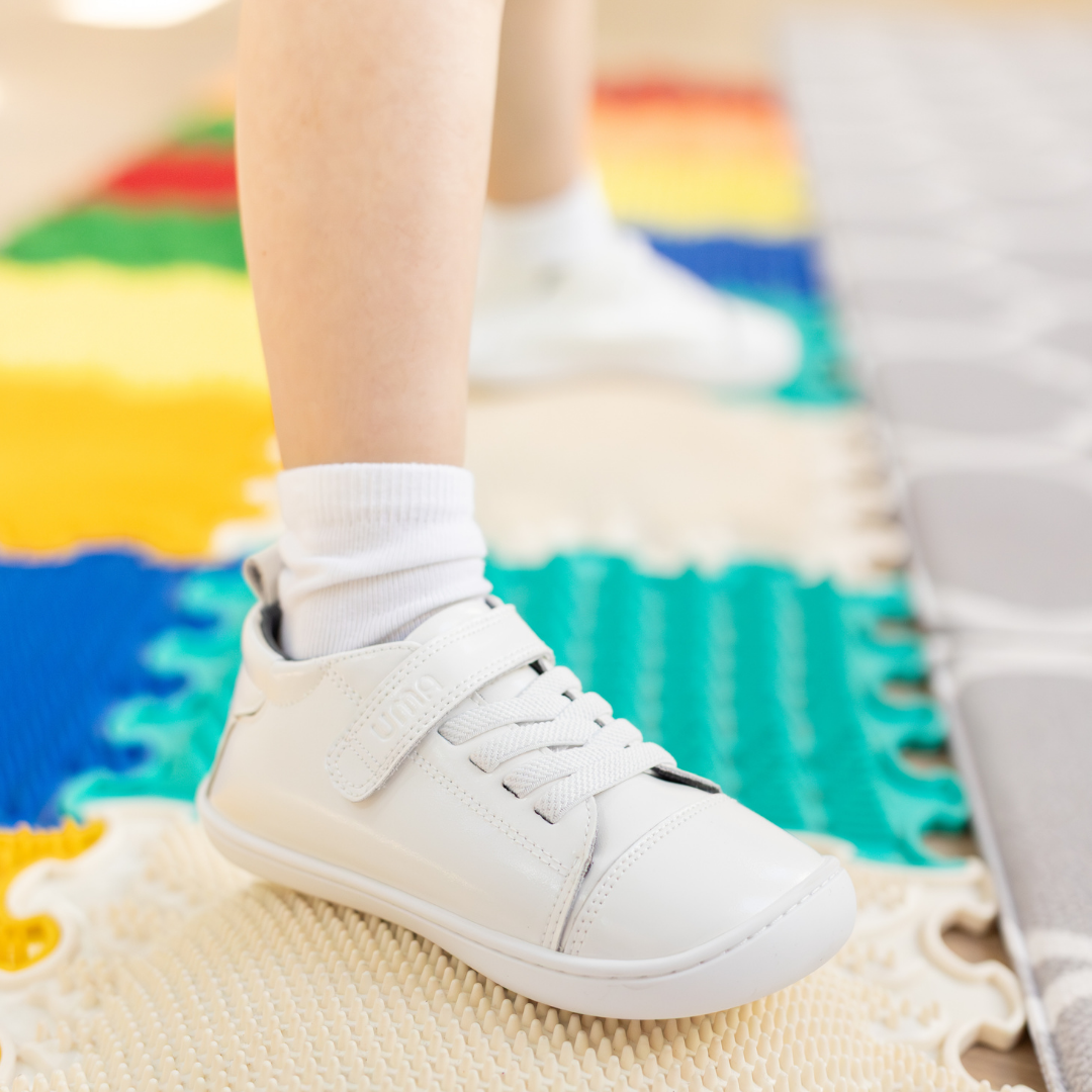 Zapatilla escolar barefoot blanca modelo Cloud con elásticos para toddler en uso vista lateral
