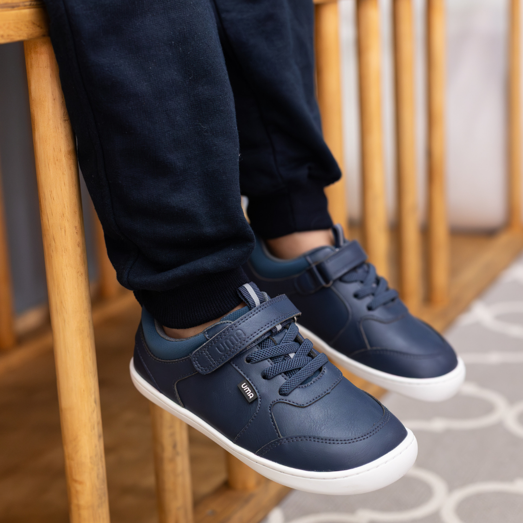 Zapatilla escolar barefoot azul marino modelo Dash con doble velcro para kids en uso vista lateral sentado
