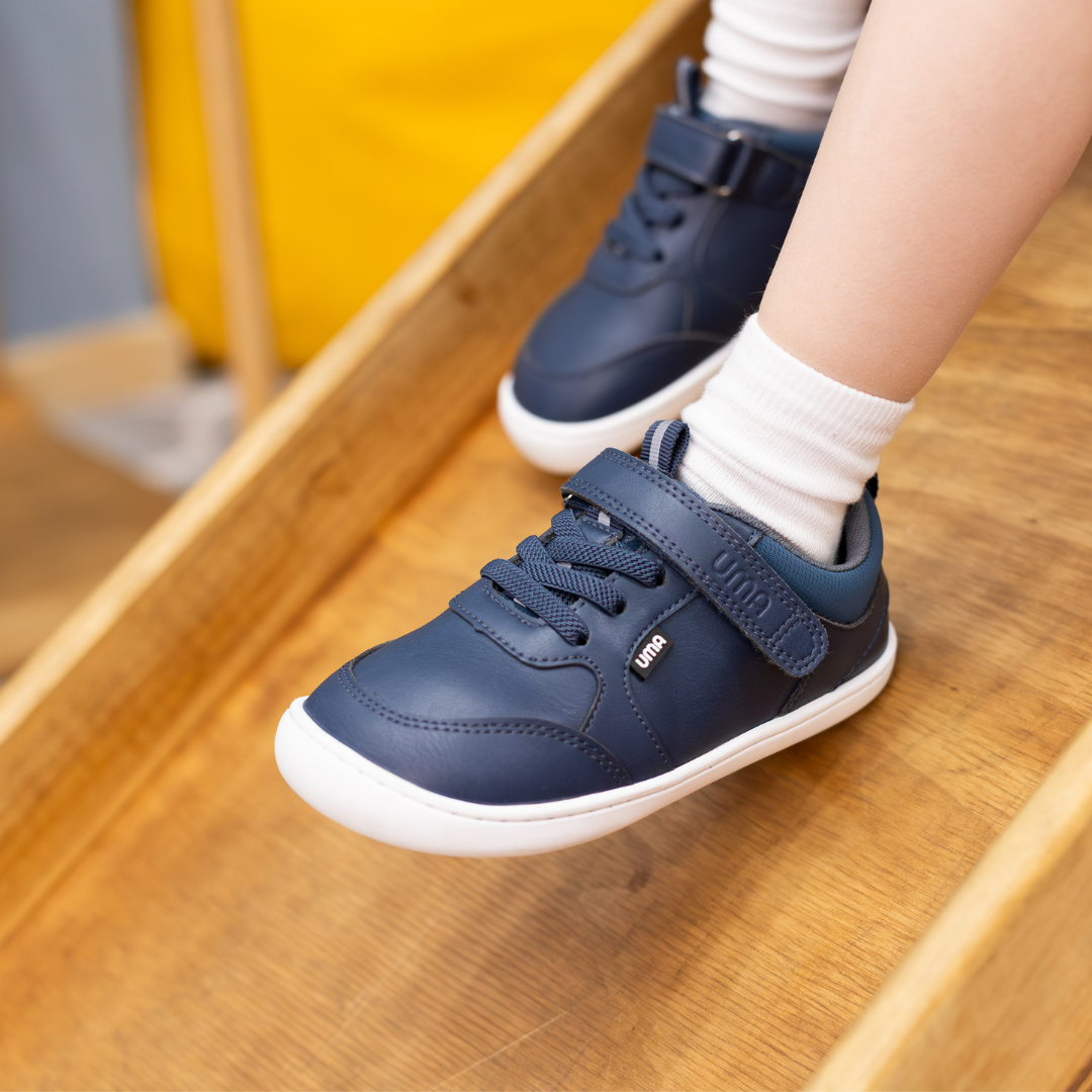 Zapatilla escolar barefoot azul marino modelo Dash con doble velcro para toddler en uso vista lateral
