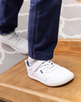 Zapatilla escolar barefoot blanca modelo Dash con doble velcro para toddler en uso vista lateral caminando
