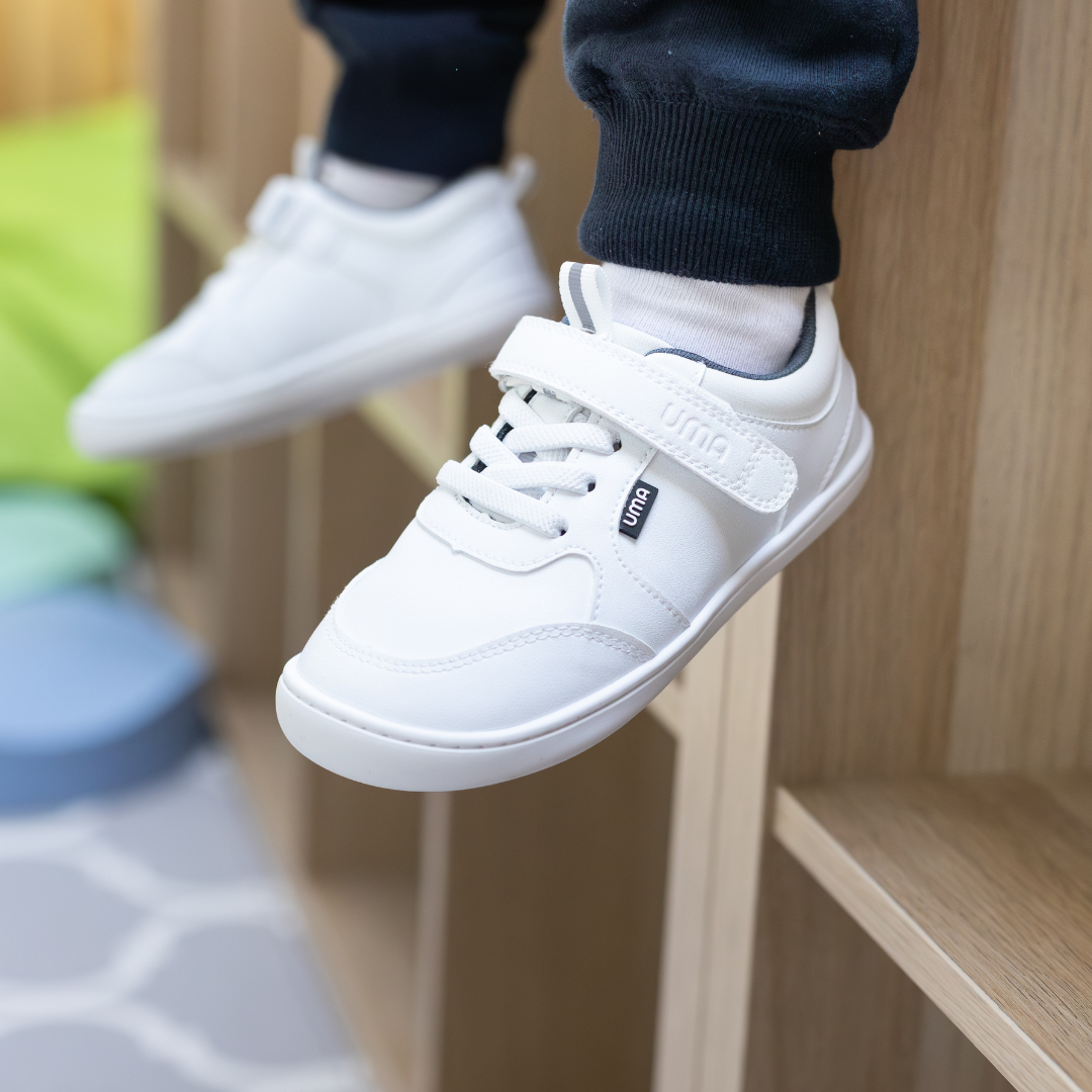 Zapatilla escolar barefoot blanca modelo Dash con doble velcro para toddler en uso vista lateral
