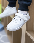 Zapatilla escolar barefoot blanca modelo Dash con doble velcro para toddler en uso vista lateral
