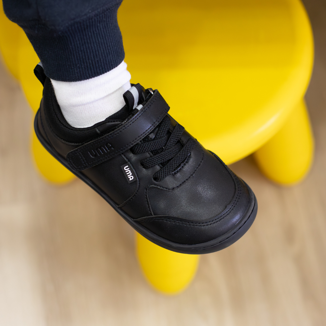 Zapatilla escolar barefoot negra modelo Dash con doble velcro para kids en uso superior
