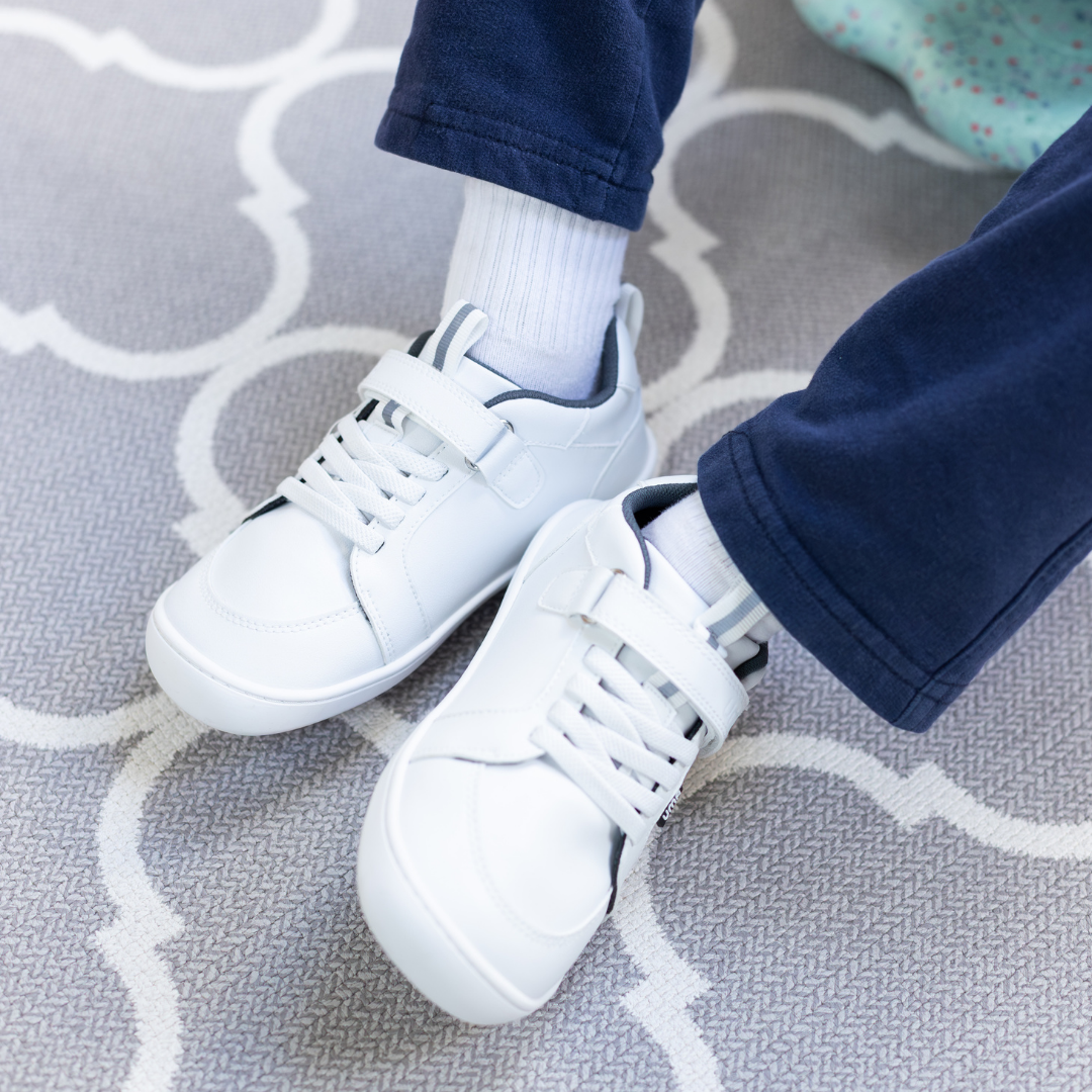 Zapatilla escolar barefoot blanca modelo Dune con velcro para kids en uso vista superior sentado
