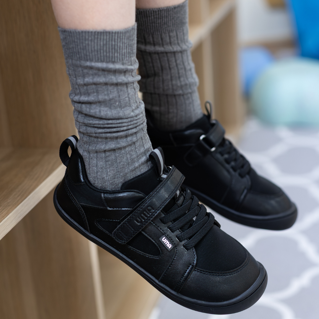 Zapatilla escolar barefoot negra modelo Dune con velcro para kids en uso vista lateral parado
