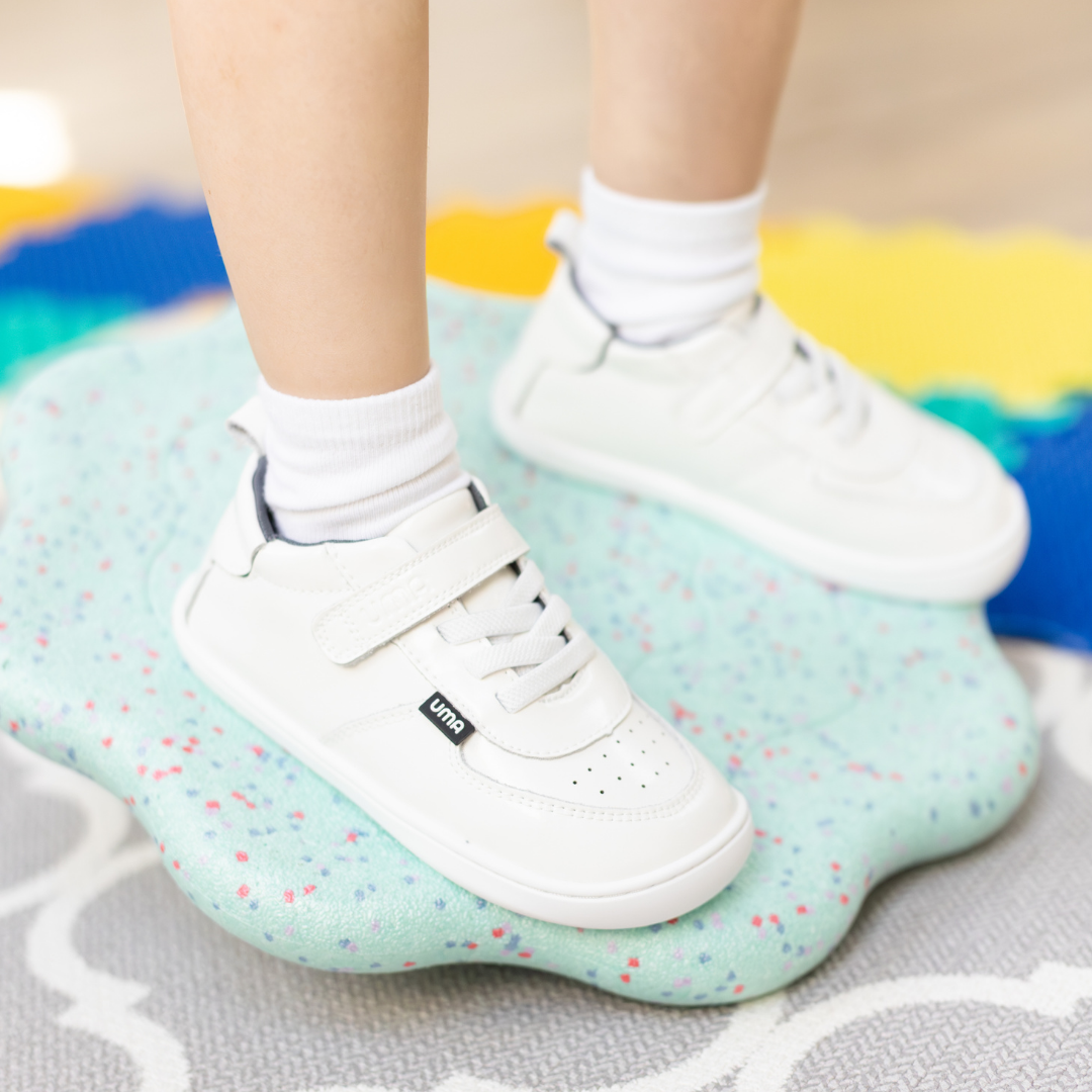 Zapatilla escolar barefoot blanca modelo Retro con velcro para toddler en uso vista lateral

