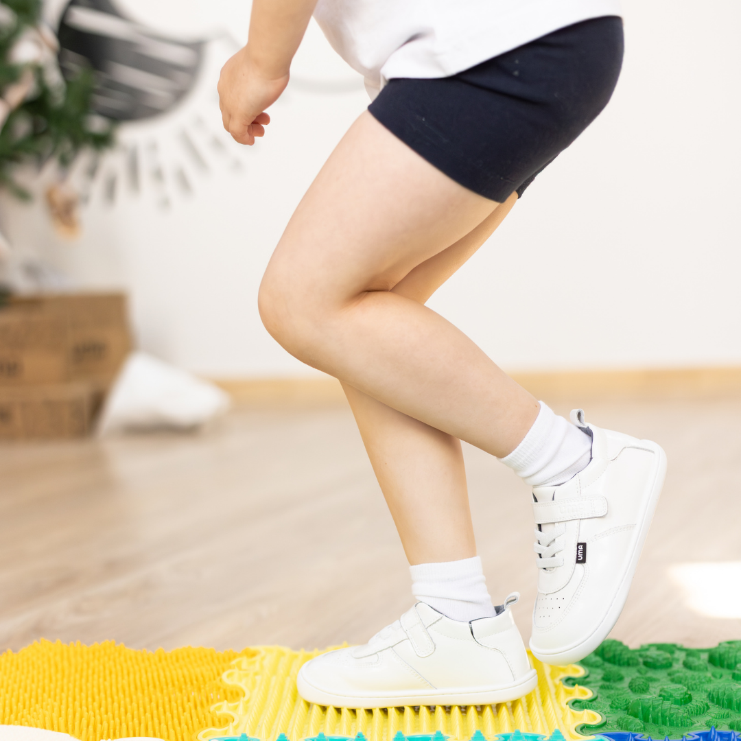 Zapatilla escolar barefoot blanca modelo Retro con velcro para toddler en uso vista lateral
