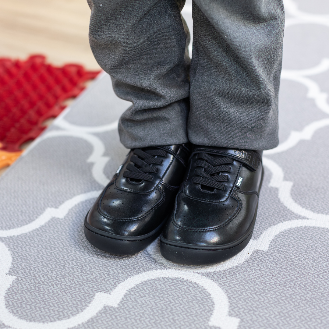 Zapatilla escolar barefoot negra modelo Retro con velcro para kids en uso vista frontal
