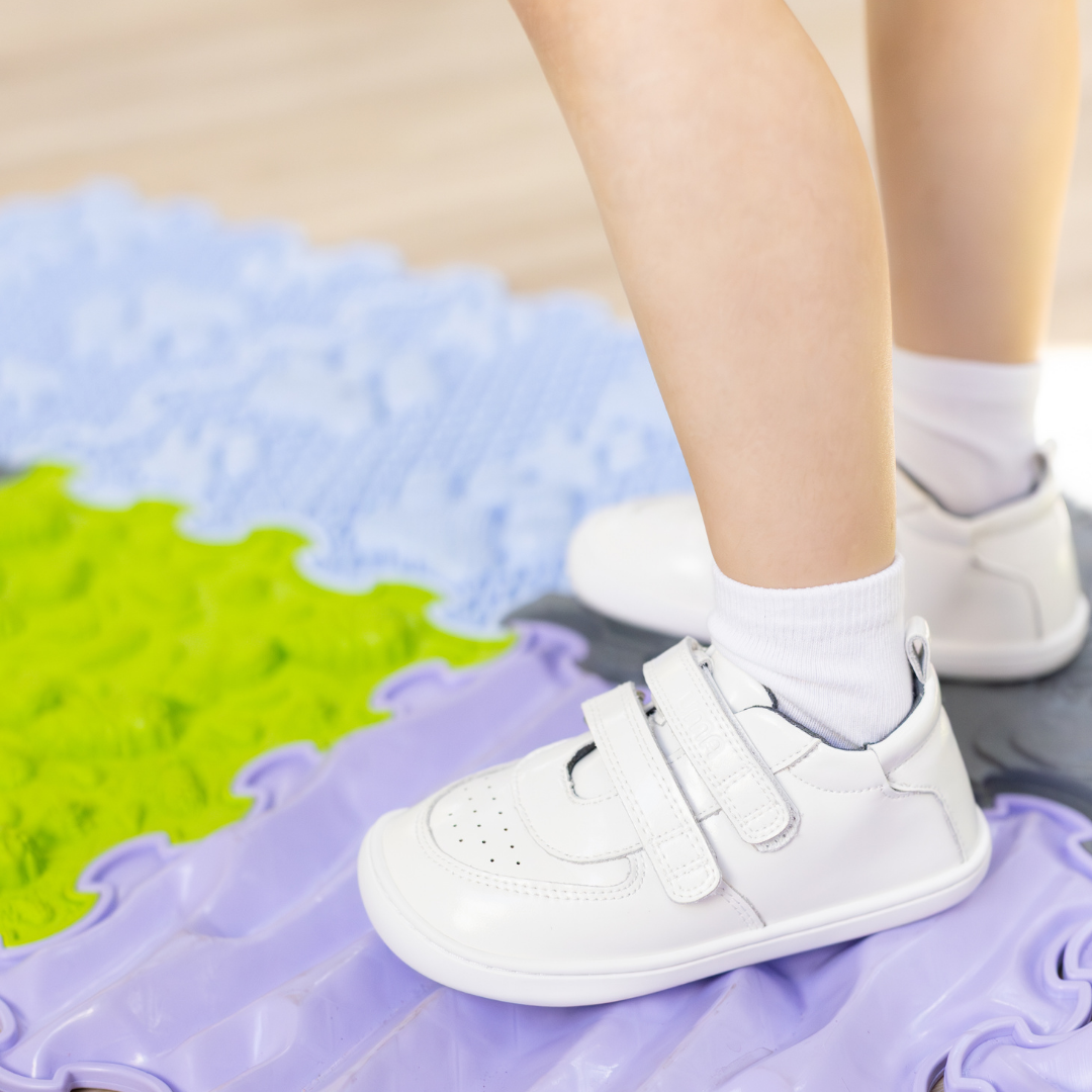 Zapatilla escolar barefoot blanca modelo Vintage con doble velcro para toddler en uso vista lateral
