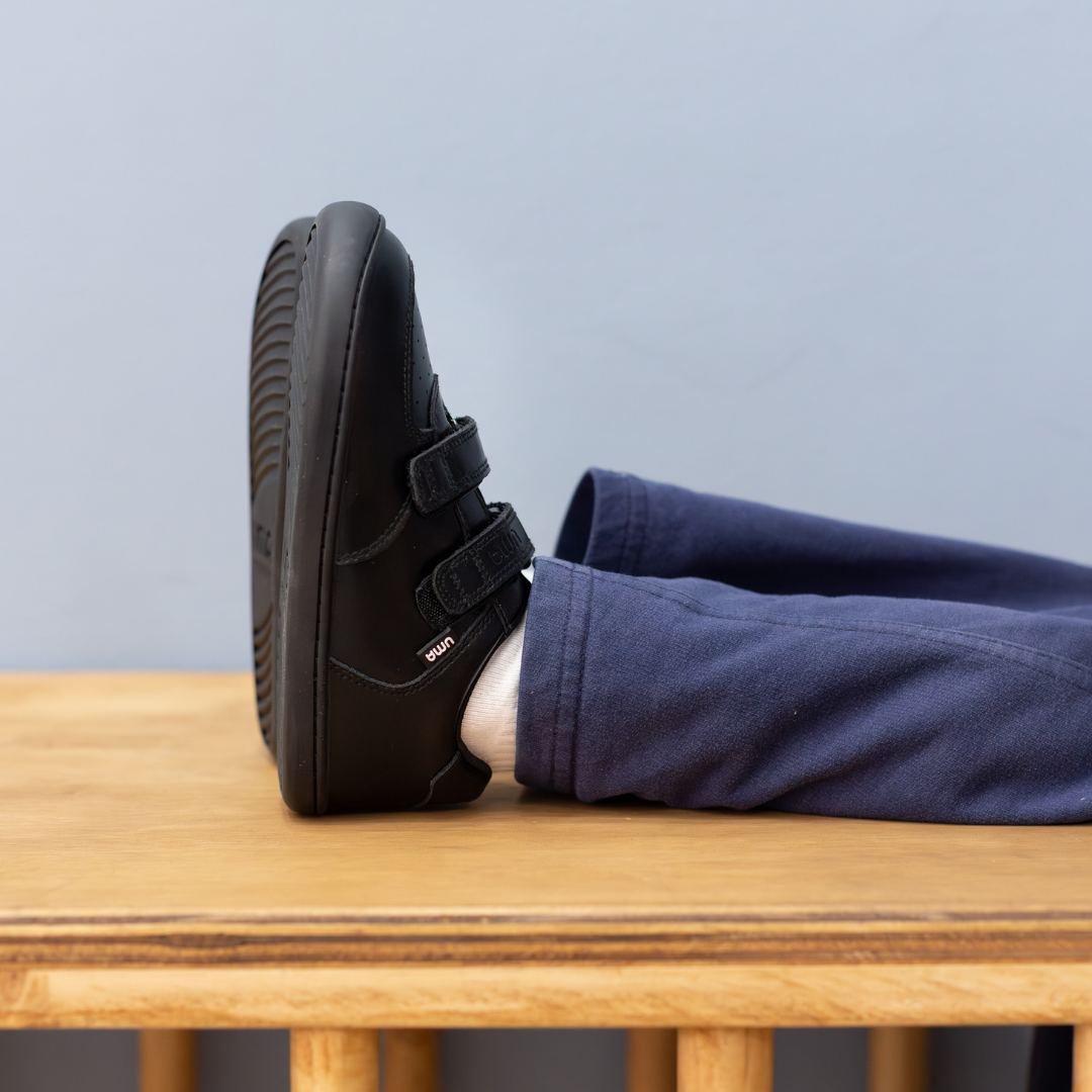 Zapatilla escolar barefoot negra modelo Vintage con doble velcro para kids en uso vista lateral
