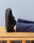 Zapatilla escolar barefoot negra modelo Vintage con doble velcro para kids en uso vista lateral
