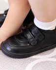 Zapatilla escolar barefoot negra modelo Vintage con doble velcro para toddler en uso vista lateral
