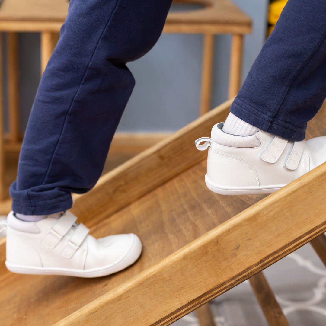 Zapatilla escolar barefoot blanca modelo Rain media caña para kids en uso vista lateral caminando
