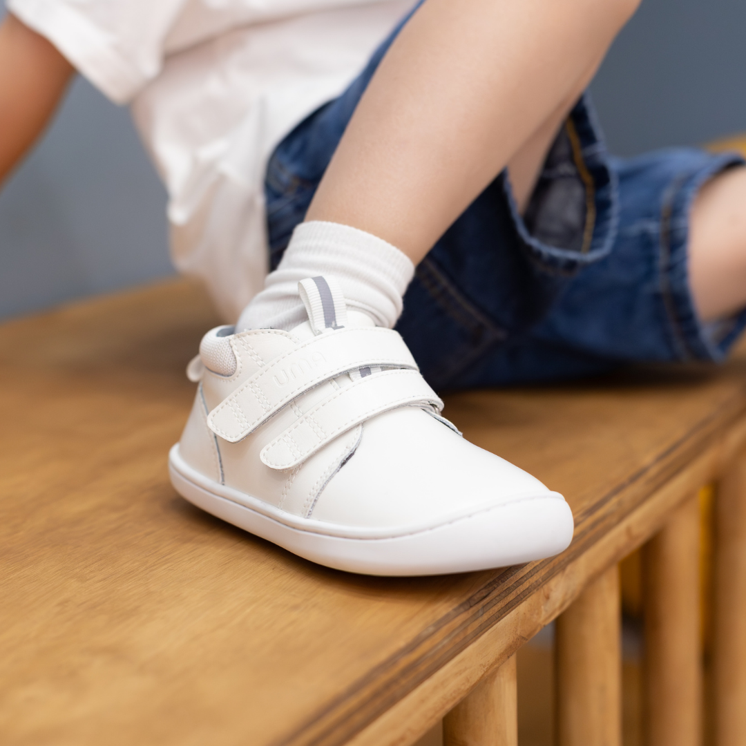 Zapatilla escolar barefoot blanca modelo Rain media caña para toddler en uso vista lateral sentado
