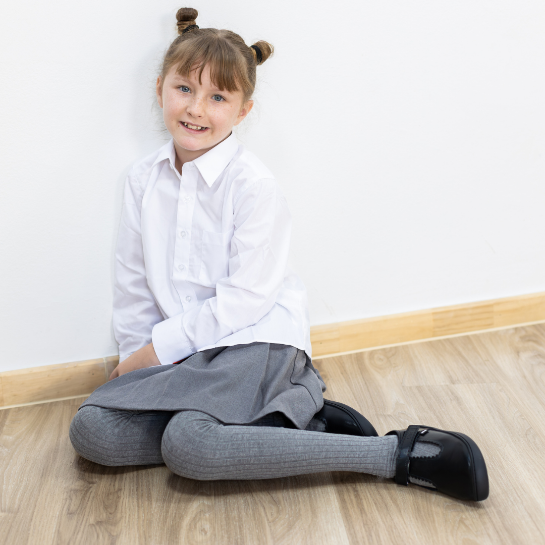 Zapato escolar barefoot negro modelo T-Bar con correa velcro para niña kids en uso niña sentada uniforme
